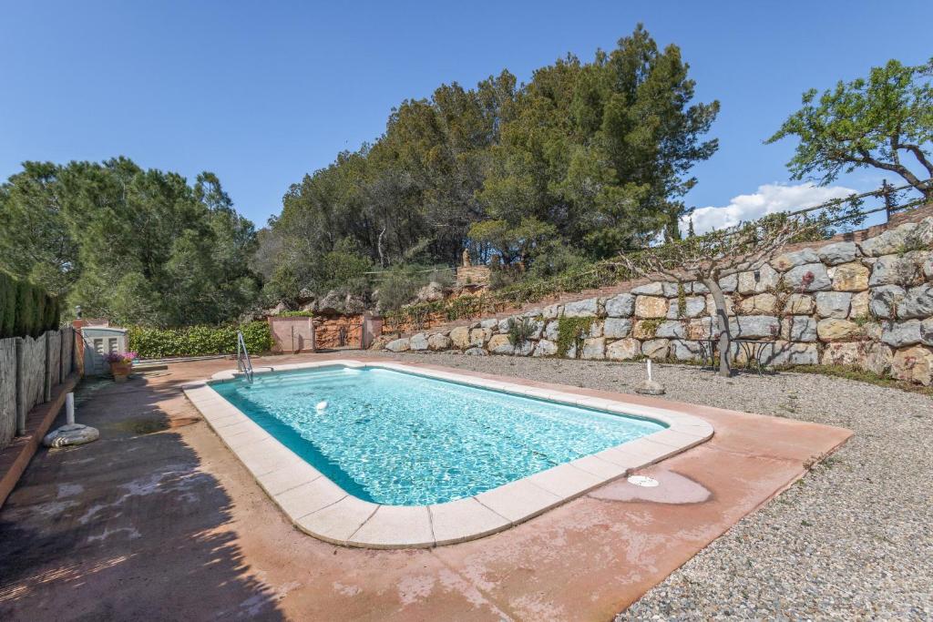 a swimming pool in front of a stone wall at Ca l'Emilli in Gélida