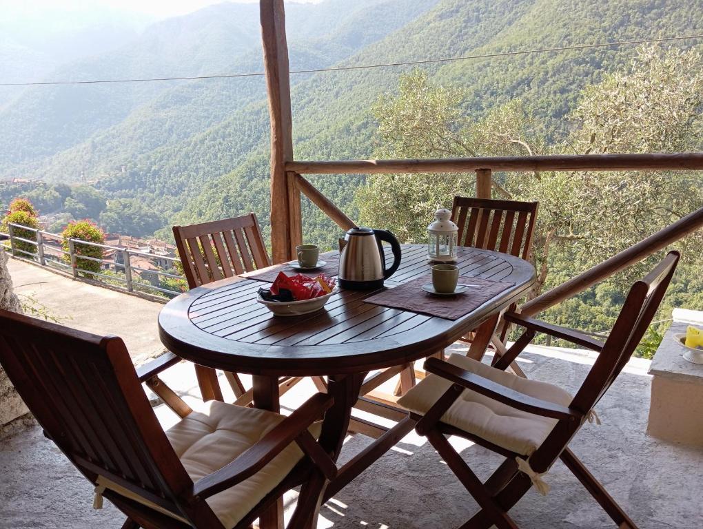 a table with a kettle and a bowl of fruit on a balcony at Agriturismo U' Spigu Nonna Annetta in Nasino