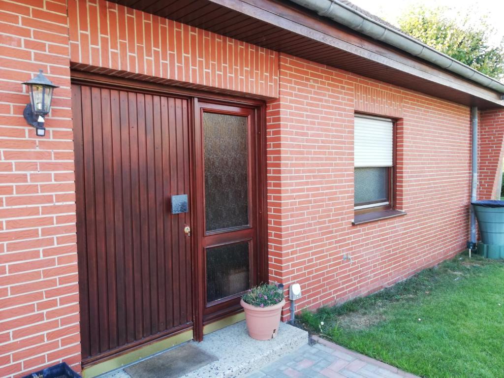 a red brick house with a wooden door and a plant at Luitje Gasthuus in Krummhörn