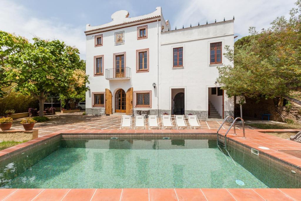 a swimming pool in front of a house at Masia Sant Miquel in Canet de Mar