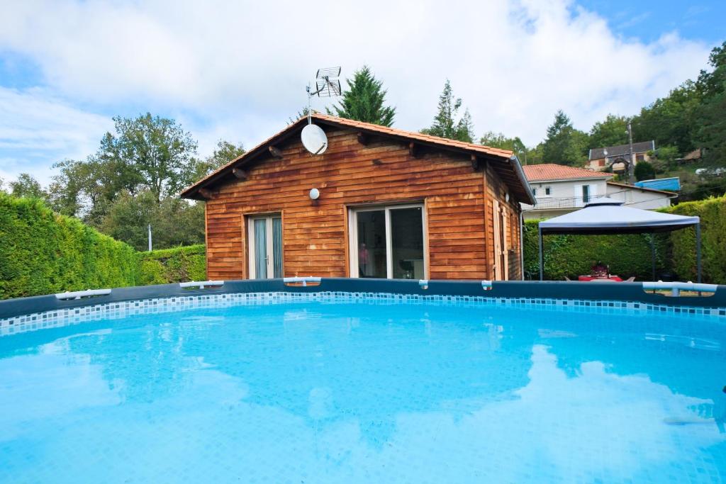 a log house with a swimming pool in front of it at Chalet avec piscine privée in Savignac-les-Églises