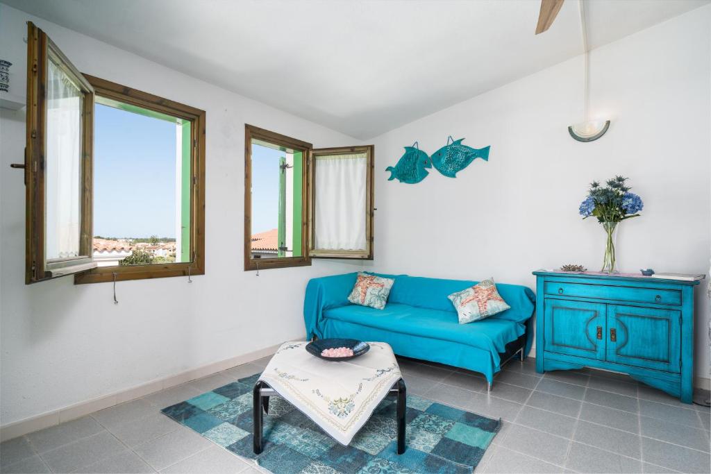 a living room with a blue couch and windows at Azzurra in Orosei