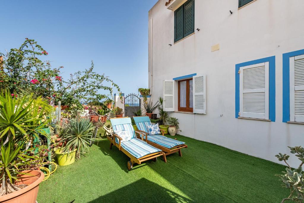 a patio with two lounge chairs on the grass at Casa Leo in Calasetta