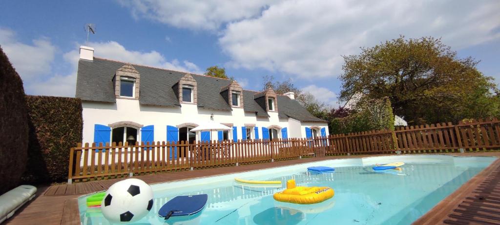 a pool with a soccer ball and chairs in front of a house at Madig Azul Maison Piscine Chauffée in La Trinité-sur-Mer