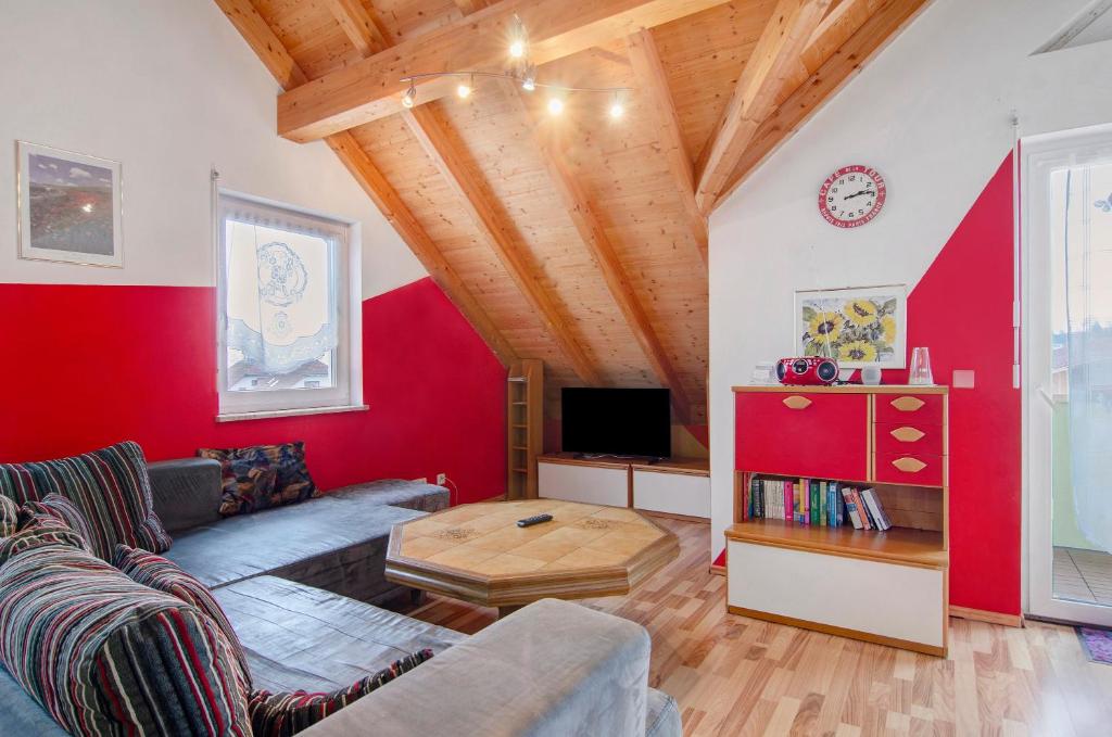 a living room with a couch and a red wall at Ferienwohnung Saupp in Immenstaad am Bodensee