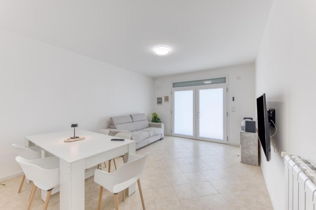 ein weißes Wohnzimmer mit einem weißen Tisch und Stühlen in der Unterkunft Leuca di Bolina in Santa Maria di Leuca
