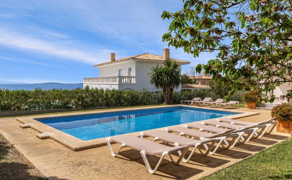 a swimming pool with lounge chairs and a house at Sa Torre in Llucmajor