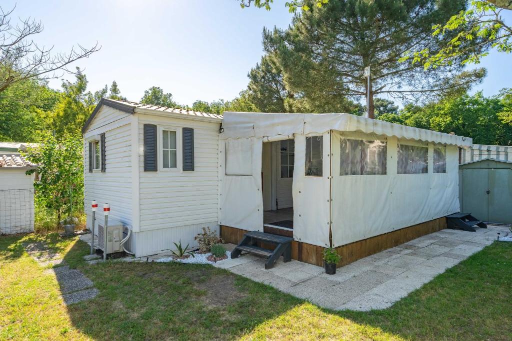 a white shed with a patio in a yard at Mh 229 La Tremblade in La Tremblade