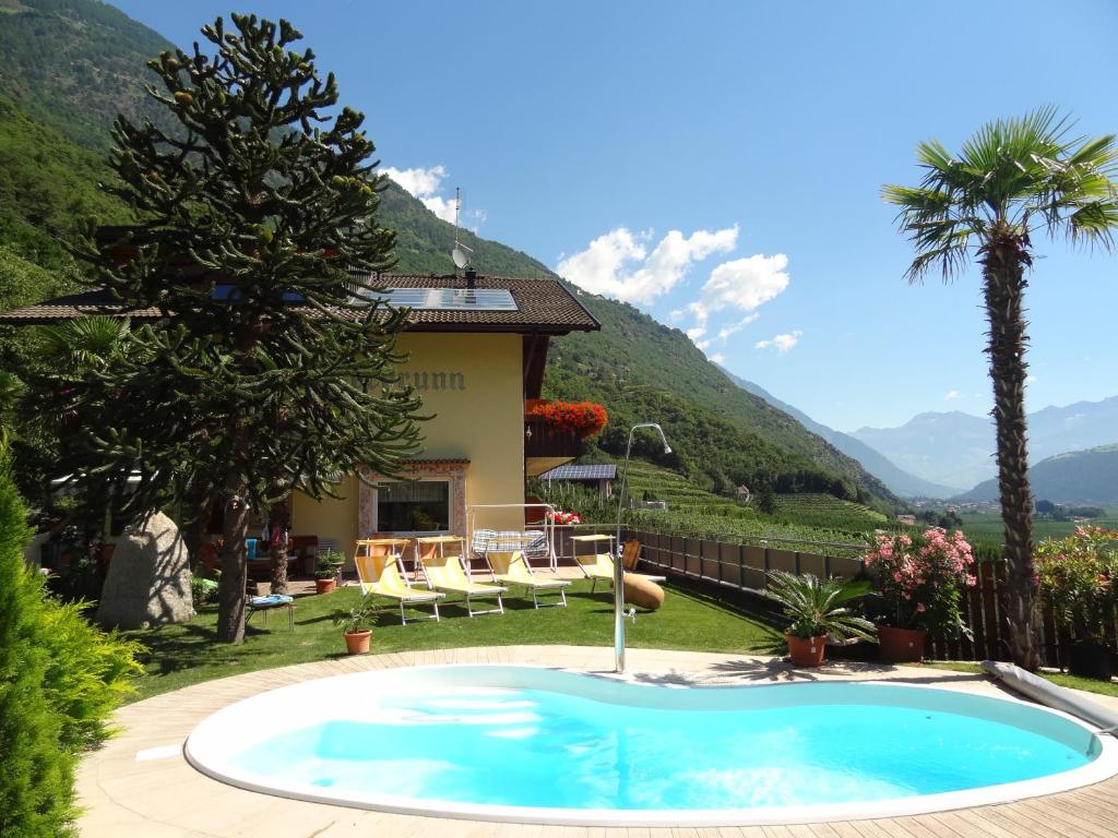 a swimming pool in front of a house with mountains at Ferienwohnungen Oberbrunnhof in Naturno