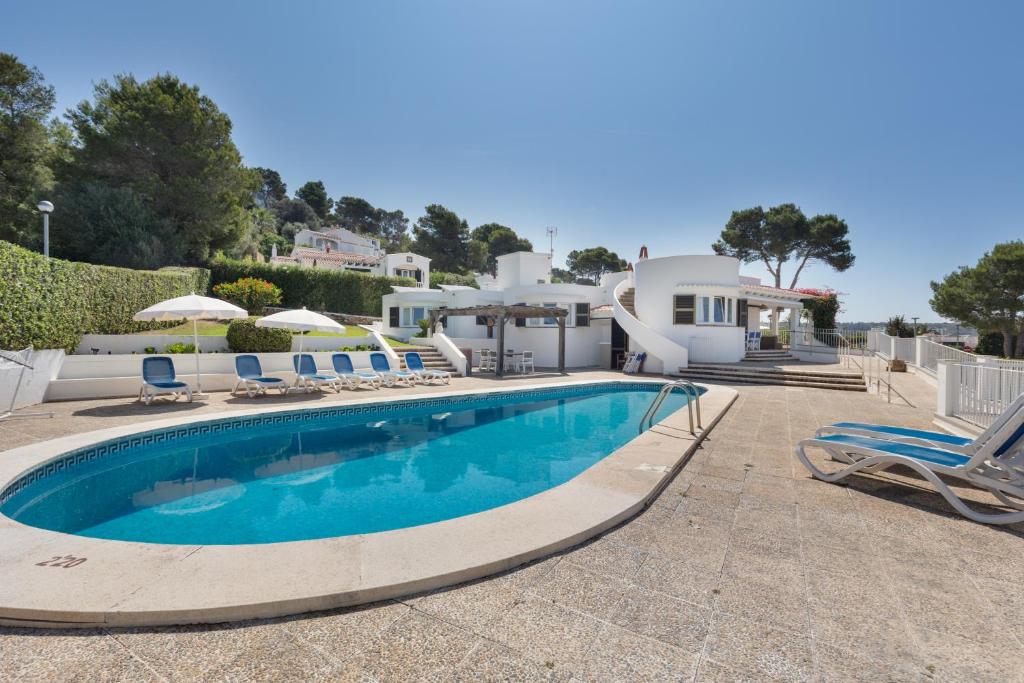 a swimming pool with chairs and a house at V206 Villa Isabel in Son Bou