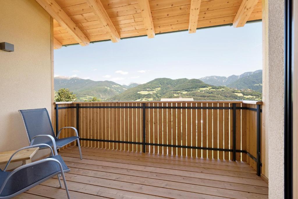 a balcony with chairs and a view of mountains at Teutenhofer Apfel in Feldthurns