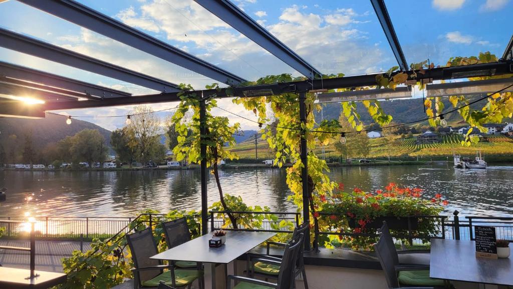 a patio with tables and chairs and a view of a river at Hotel Haus Burg Metternich in Beilstein