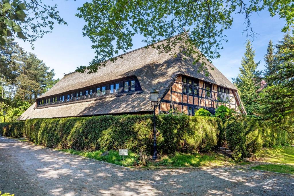 a house with a thatched roof on a hedge at Wohnen im Heidehaus in Sankt Dionys