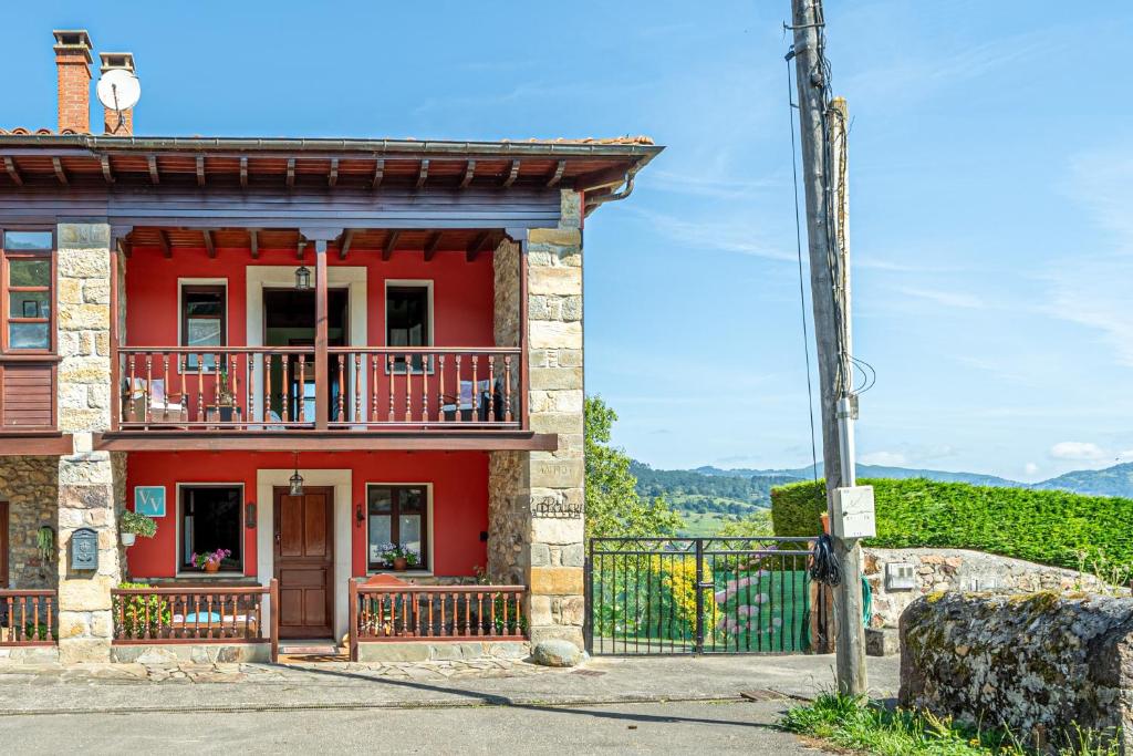 a red house with a balcony on a hill at Paz y Tranquilidad in Melarde