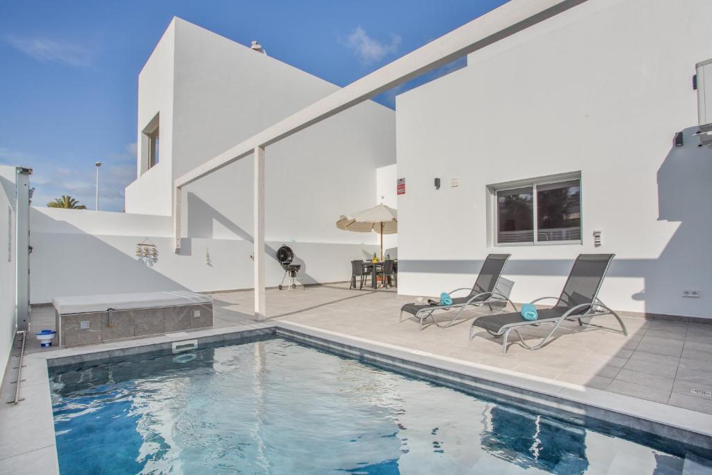 a house with a swimming pool and two chairs at Casa Gara Fuerteventura in Gran Tarajal