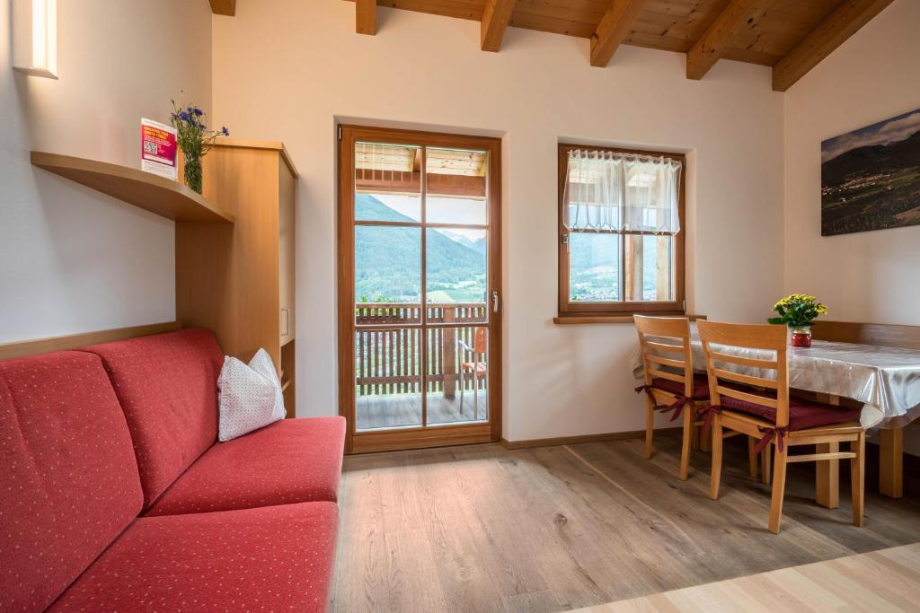 a living room with a red couch and a table at Kreuzhof rechts in Novacella