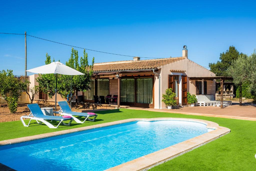 a house with a pool and two chairs and an umbrella at S'Hostalet in Islas Baleares
