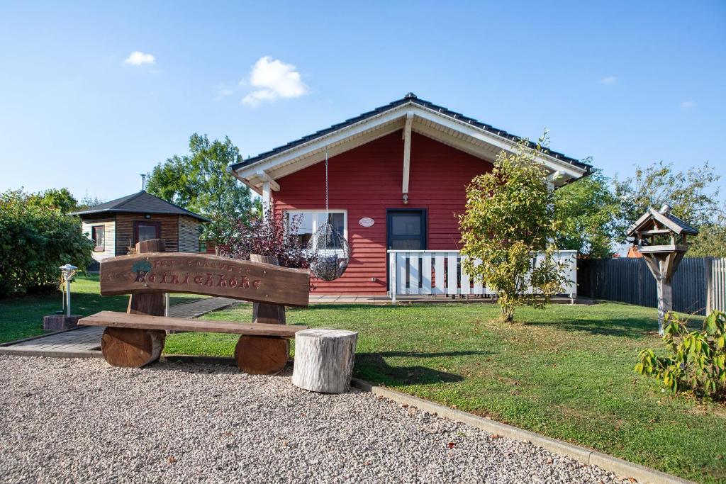 a wooden bench in front of a red house at Ferienhäuser Hainichhöhe in Hörselberg-Hainich
