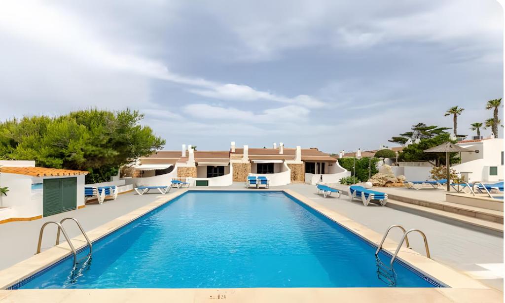 a swimming pool with blue chairs and a resort at Villa Estrellas 2 in Cala en Bosc