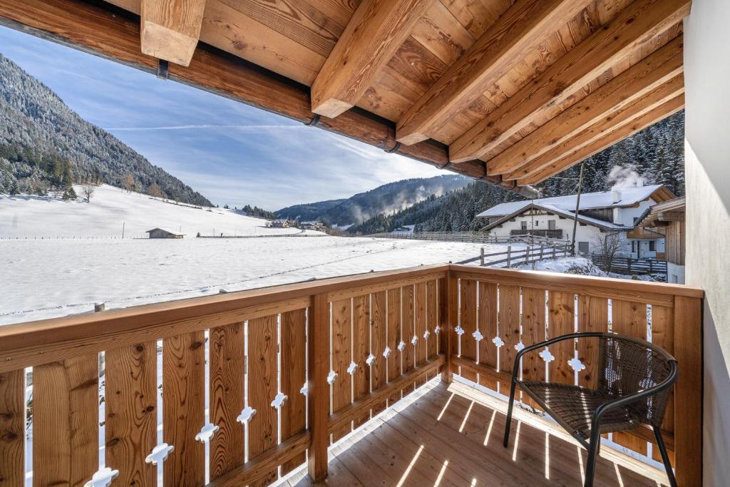 a balcony with a chair and snow covered mountains at Ferienhaus Larch Soge Apt Karin in Racines