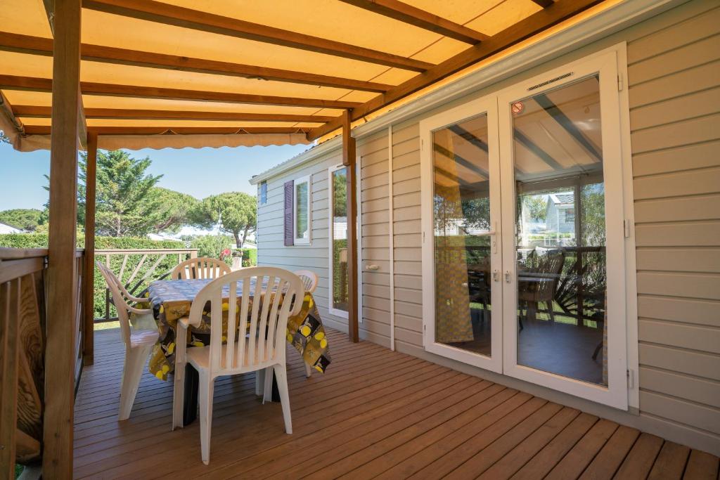 a patio with a table and chairs on a deck at Mobilhome 373 in Lattes