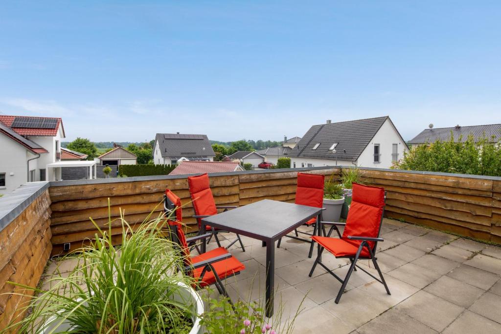 a patio with red chairs and a table on a fence at Ferienwohnung Panoramablick in Leipheim