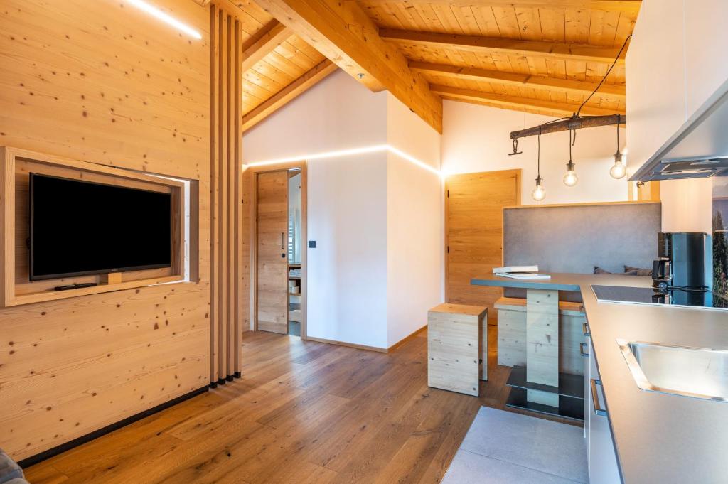 a kitchen with wooden walls and a flat screen tv at Schreiberhof Charme in Laion