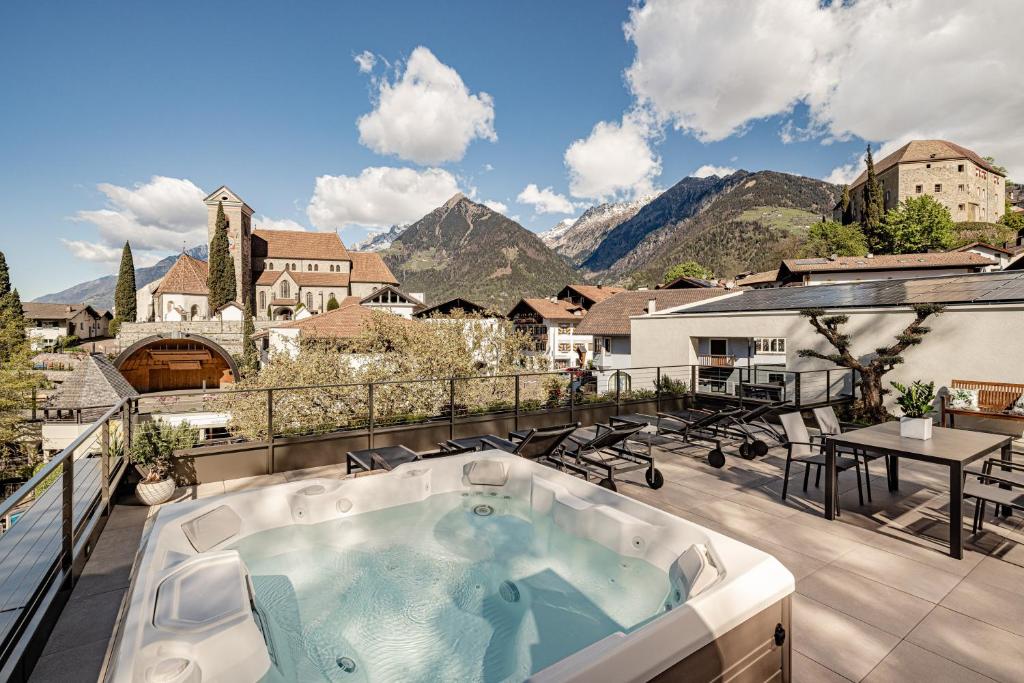 a hot tub on a balcony with mountains in the background at Schenna Chalet - Apt Stefan in Schenna