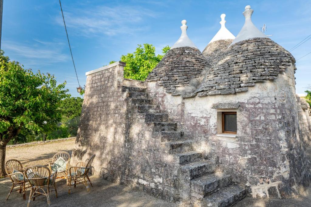 an old stone building with stairs and tables and chairs at I Trulli di Dona Filomena in Selva di Fasano