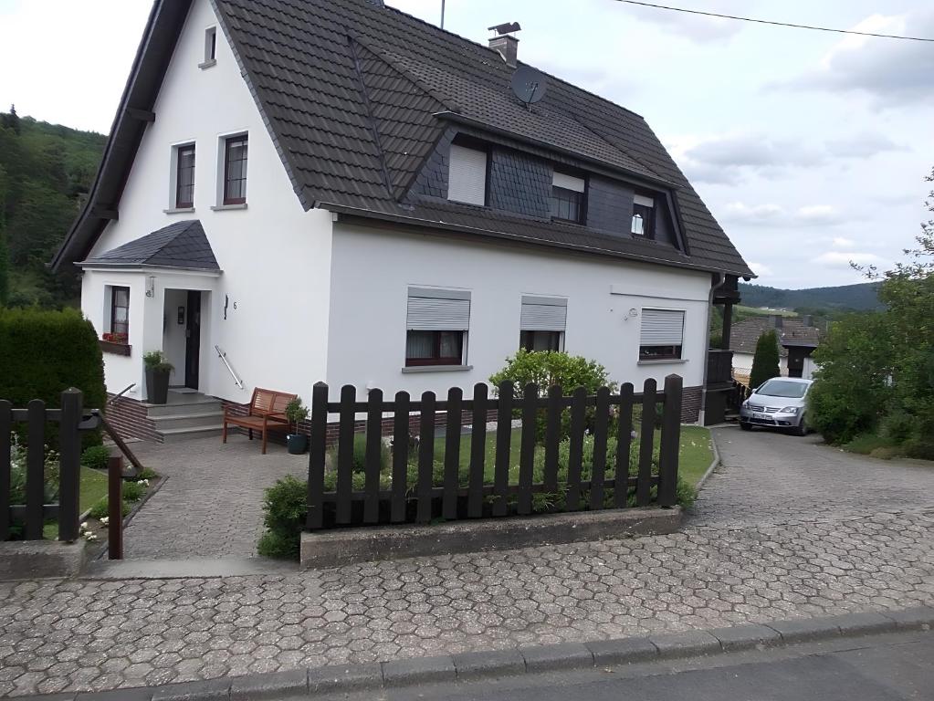 a white house with a black roof and a fence at Ferienwohnung Heinz Romes in Wimbach