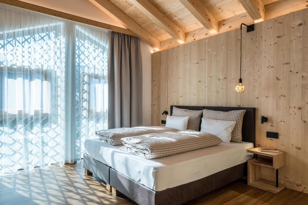 a bedroom with a bed and a large window at Les Ciases Chalets Dolomites Apt 6 in San Vigilio Di Marebbe