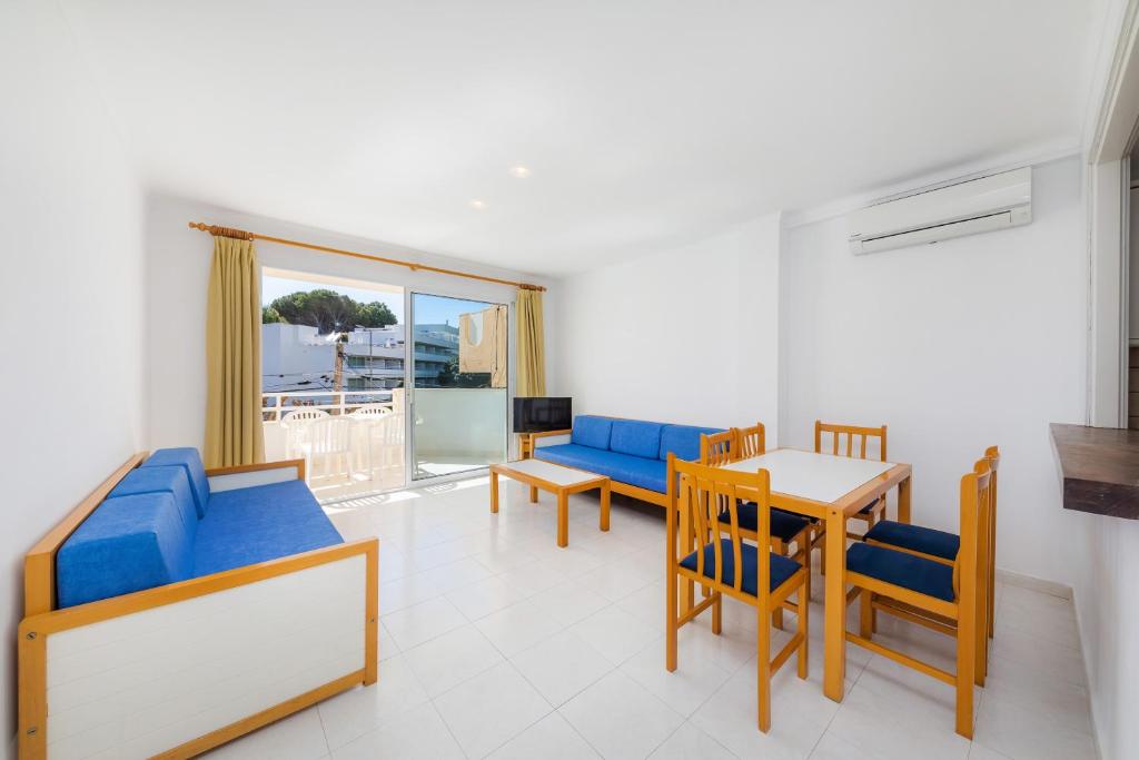a living room with blue furniture and a table and chairs at Apartament Massanet ba in Canyamel