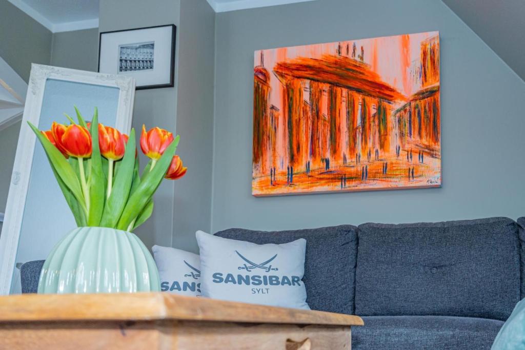 a vase of flowers on a table with a couch at Gemütliche Wohnung Reet-Pool-Sauna in Keitum