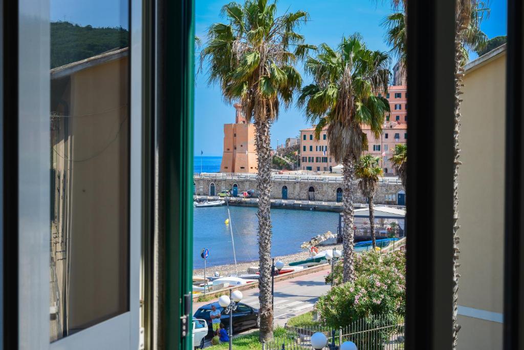 a window with a view of a harbor and palm trees at Loft il Mare Rio Marina front sea in Rio Marina