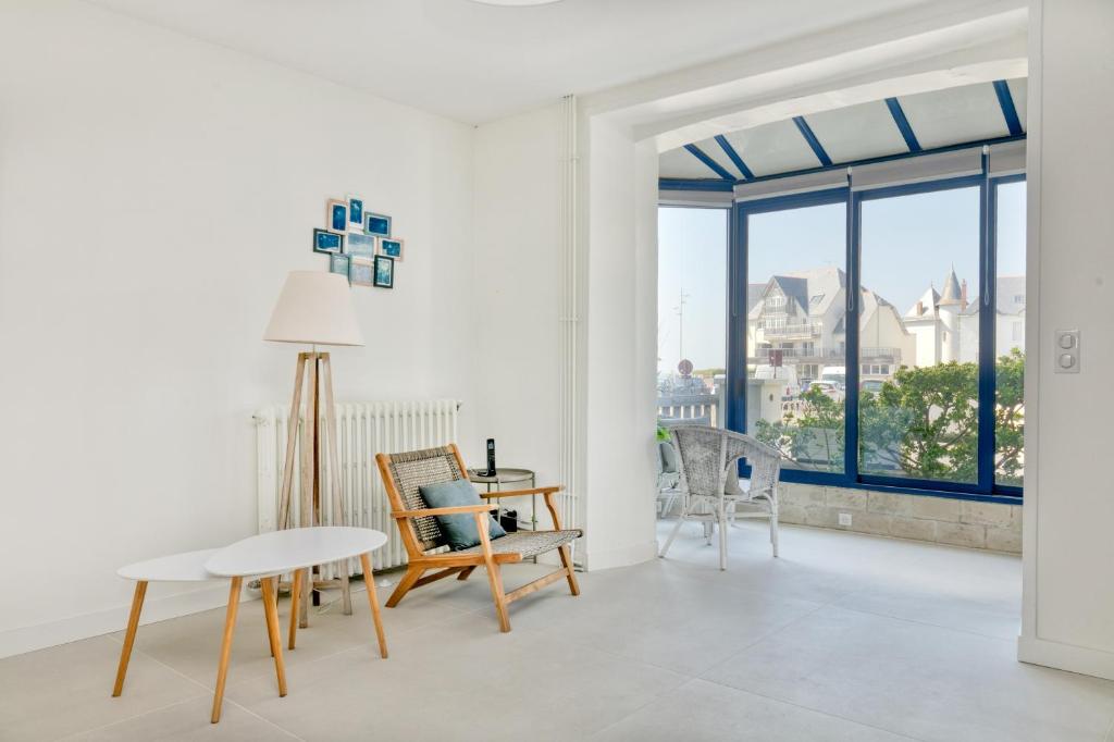 a living room with a table and chairs and windows at La Maison de Port Lin in Le Croisic