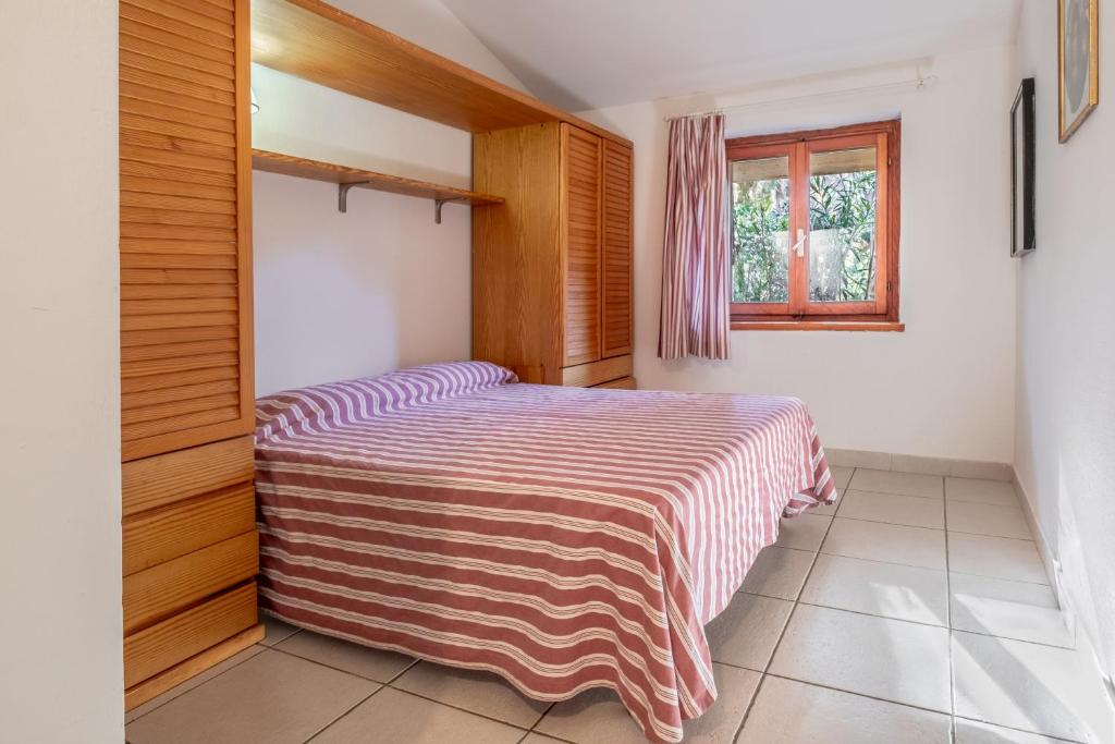 a bedroom with a bed with a striped blanket at La Capannuccia B in Ansedónia
