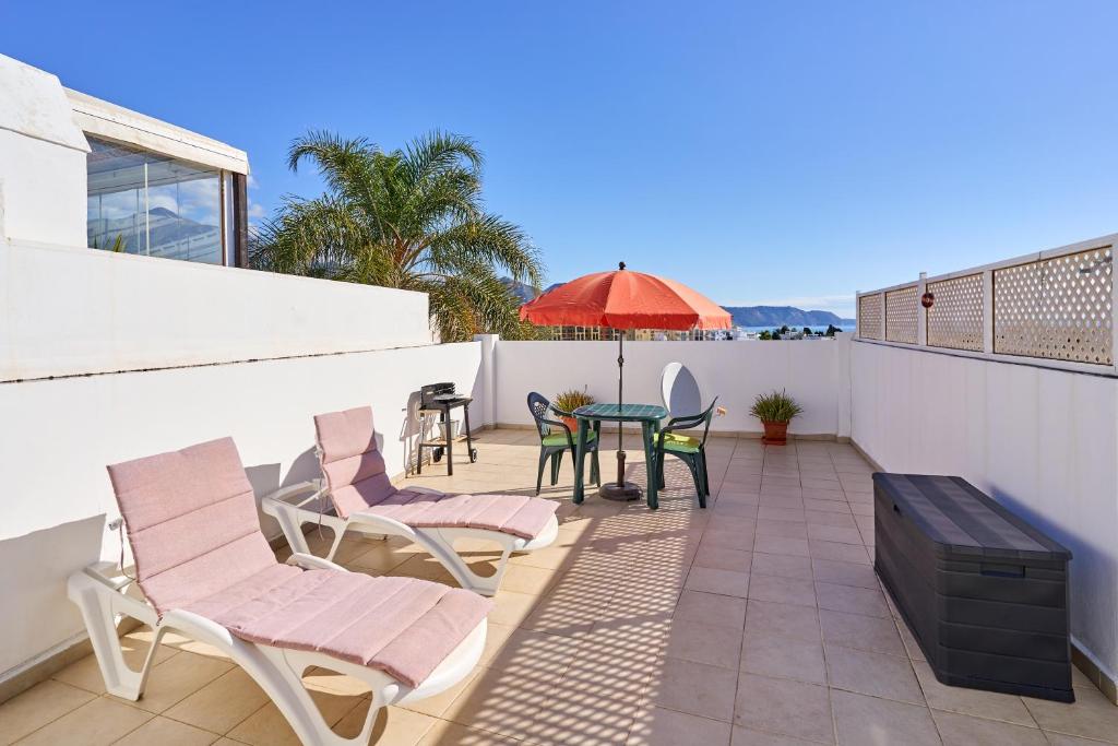 a patio with chairs and a table with an umbrella at Apartamento Fernandita in Nerja