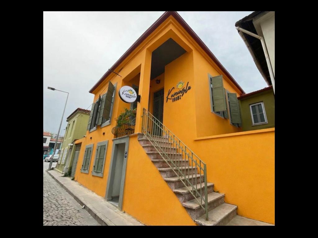 a yellow building with stairs and a clock on it at Kavcıoğlu Rooms in Urla