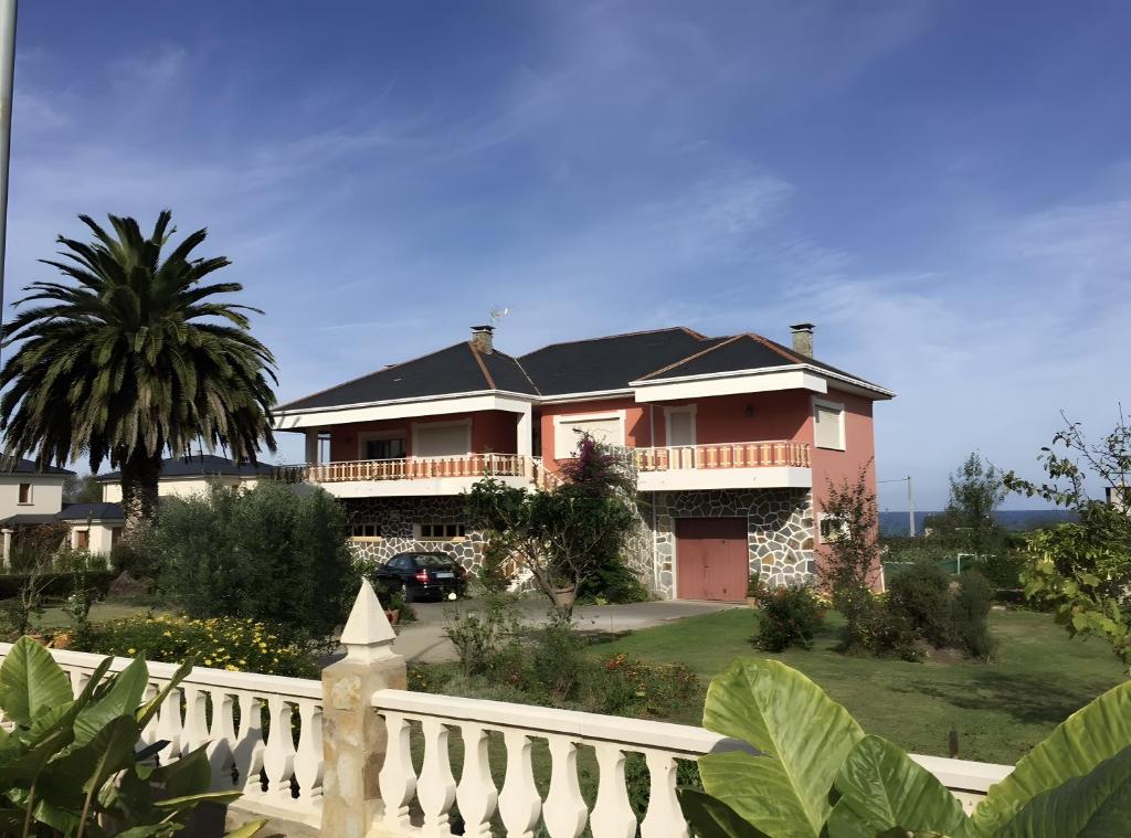 a large pink house with a white fence at Villa Neli Playa in Foz