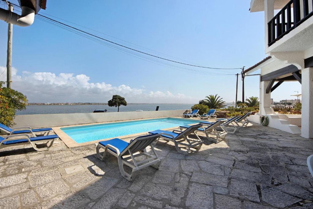 a swimming pool with chaise lounge chairs next to a house at Casa Do Bico Da Biarritz in Costa Nova