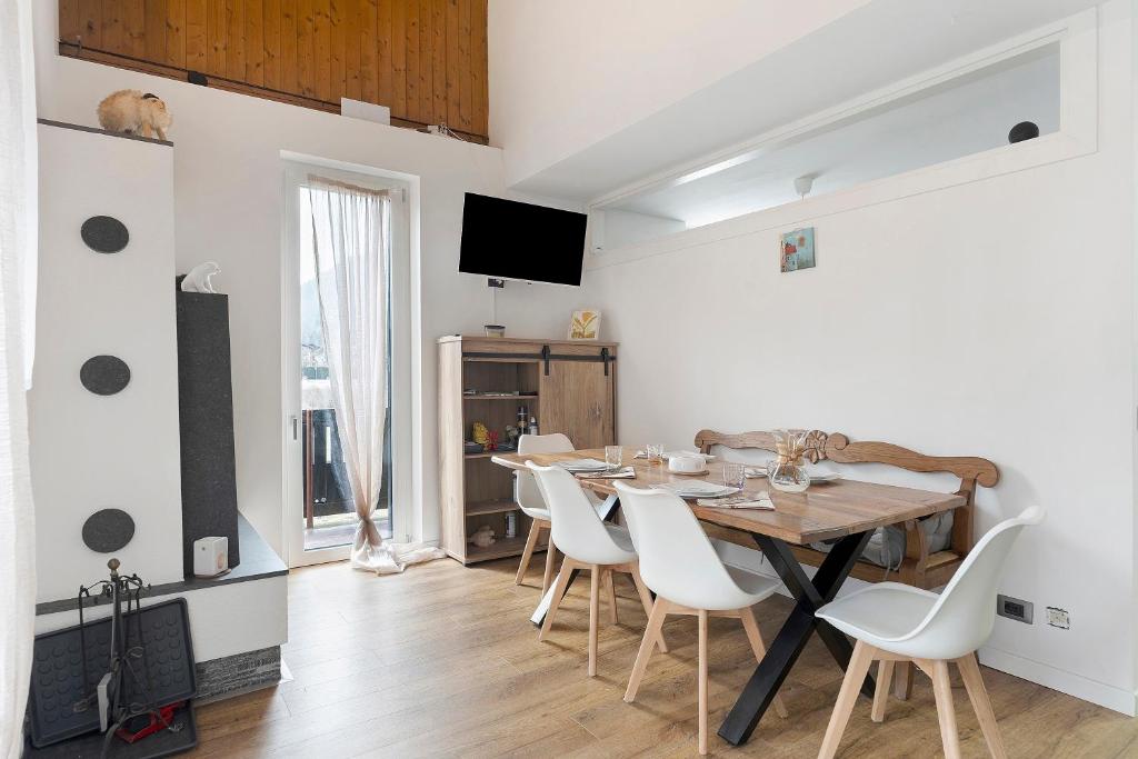 a dining room with a wooden table and white chairs at Railway Loft Dimaro I By Immobilux in Monclassico