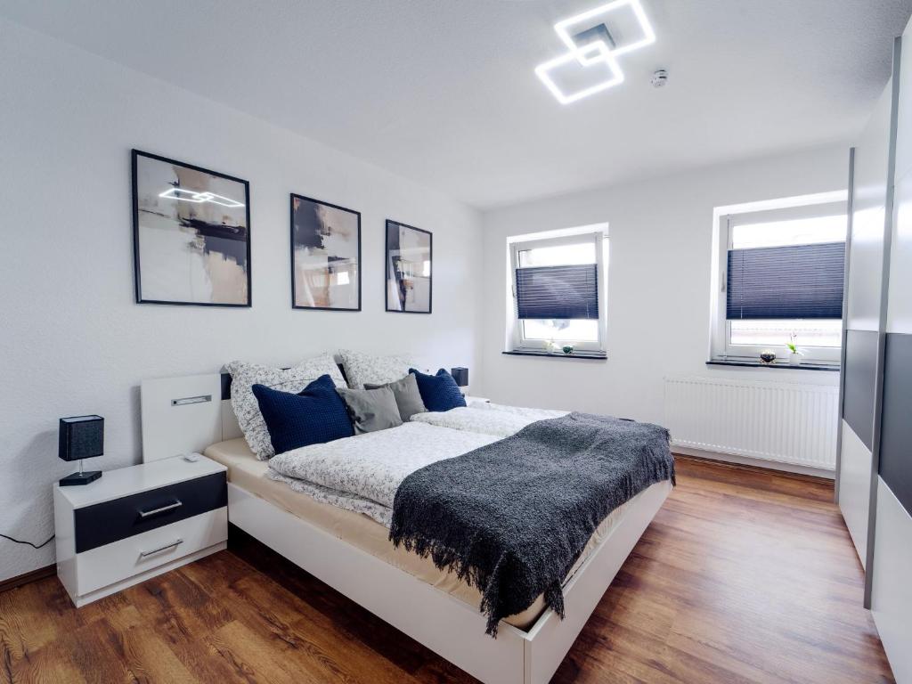 a white bedroom with a bed and three windows at Ferienwohnung Sunny in Schmallenberg