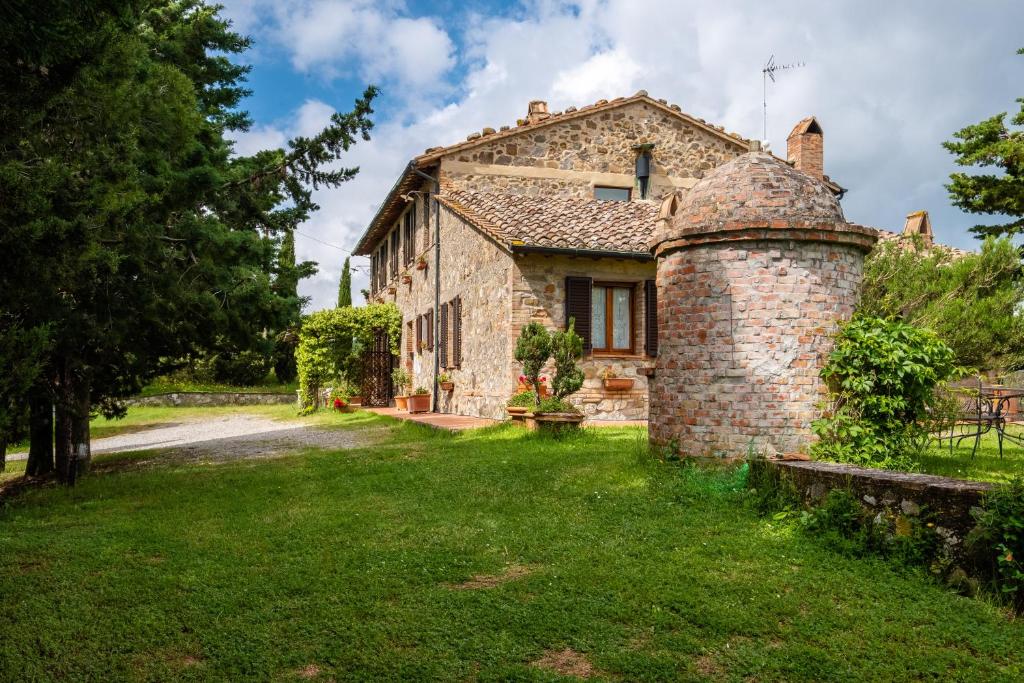 an old stone house with a chimney in a yard at Appartamento Glicine in Radicofani