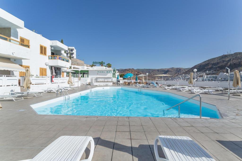 a large swimming pool in a resort with chairs at Casa Neale in Puerto Rico de Gran Canaria