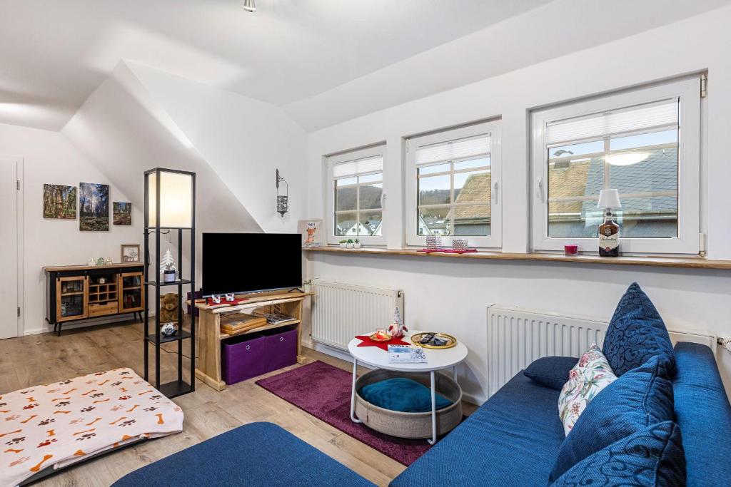 a living room with a blue couch and a tv at Ferienwohnung zum Heubalken in Schmallenberg