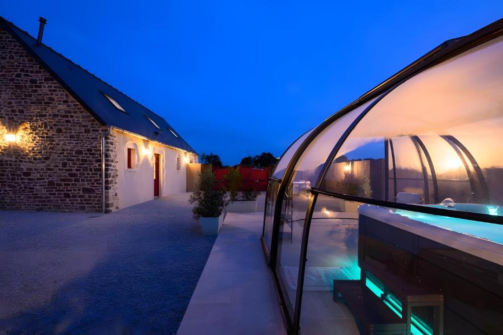 a house with a glass facade at night at L'Ascalon in Saint-Sauveur-le-Vicomte
