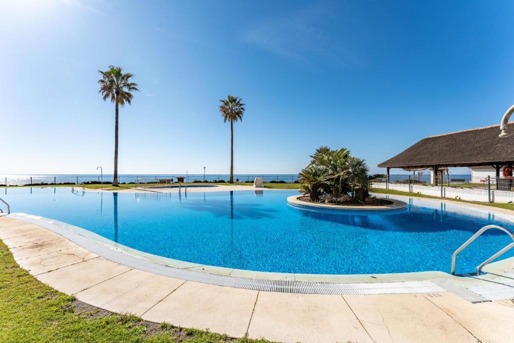 a large swimming pool with palm trees in the background at Mi capricho Beachfront Apt in Mijas