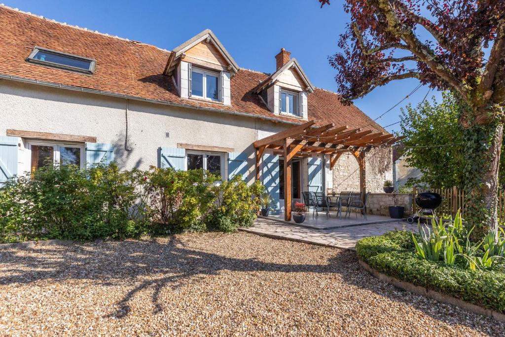 an external view of a house with a wooden pergola at La clé des Champs in Couffy