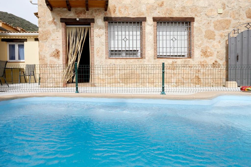 a large blue swimming pool in front of a house at Casa Calera in Arbuniel