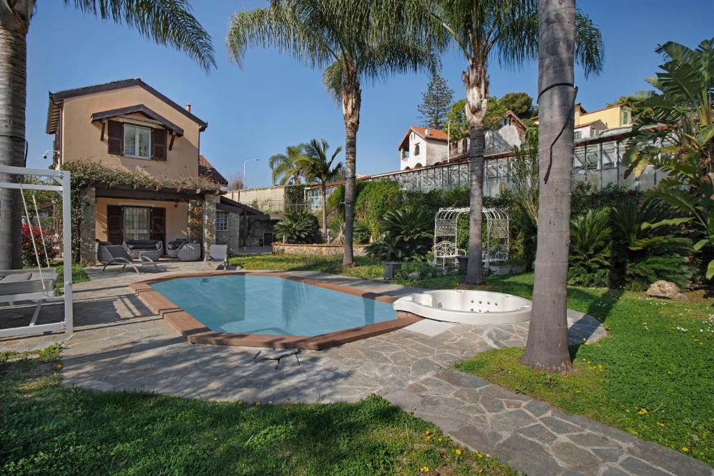 a house with a swimming pool and palm trees at Villa Vallegrande in Ospedaletti